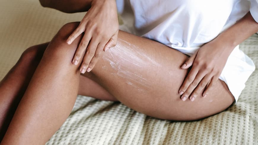 Frau trägt Bodylotion auf