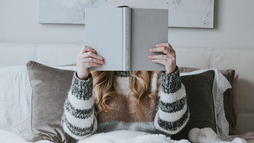 Frau liest ein Buch im Bett
