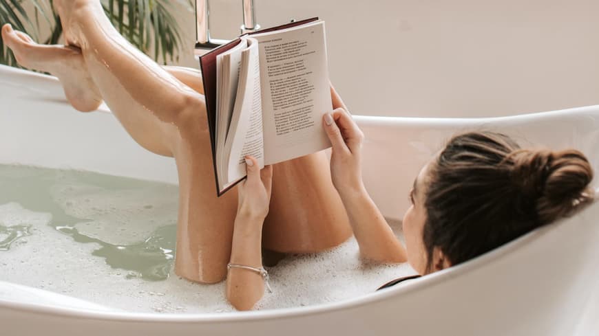 Frau liest Buch in der Badewanne