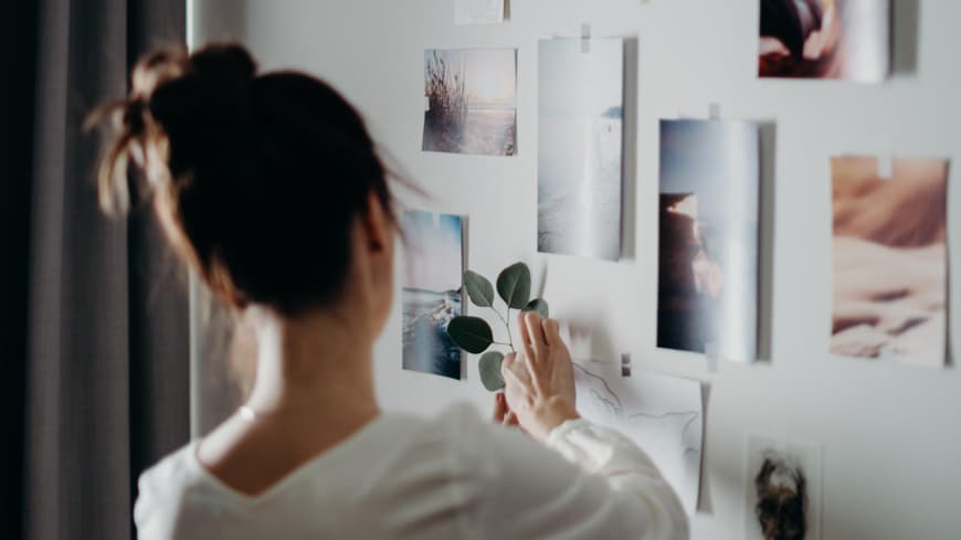 Frau dekoriert eine Wand mit Fotos
