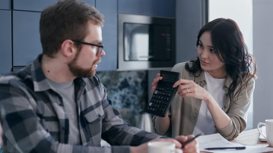 Mann und Frau sitzen am Tisch und reden über Finanzen
