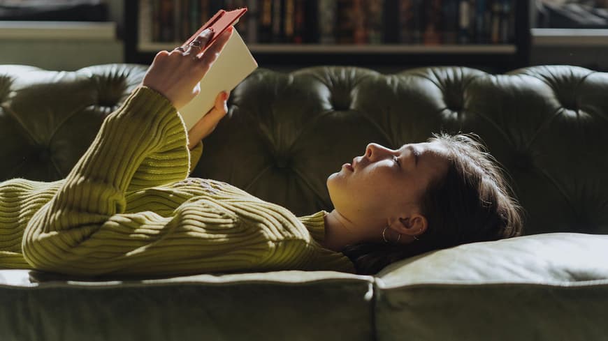 Frau liest Buch auf dem Sofa