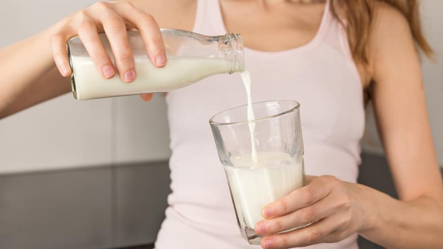 Frau gießt Milch in ein Glas