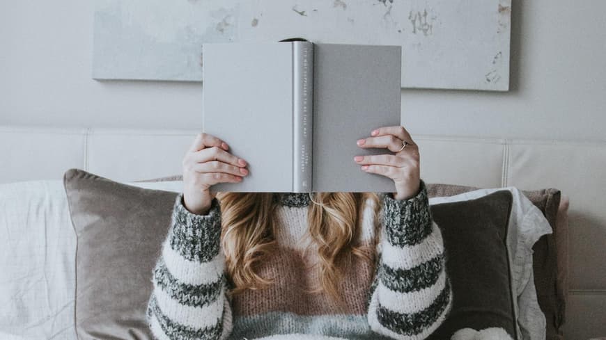 Frau liest Buch im Bett