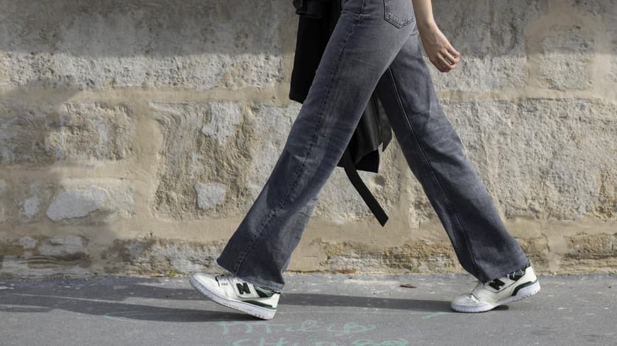 Frau trägt auf Paris Fashion Week Jeans in Grau mit Sneakern und Top Streetstyle