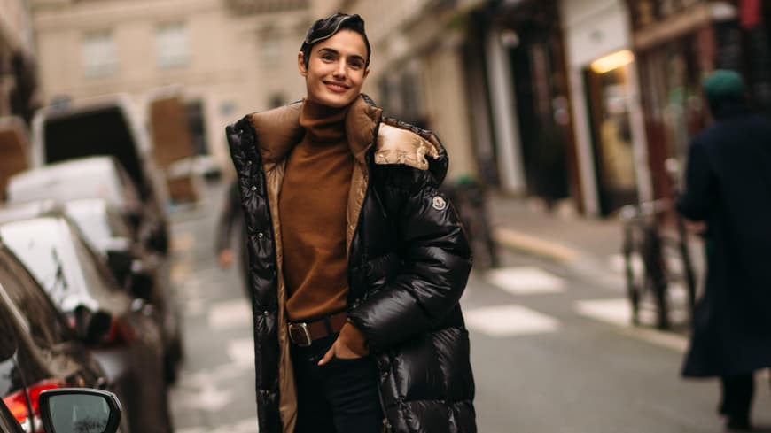 Frau trägt auf London Fashion Week schwarzen wattierten Mantel mit Stiefeletten