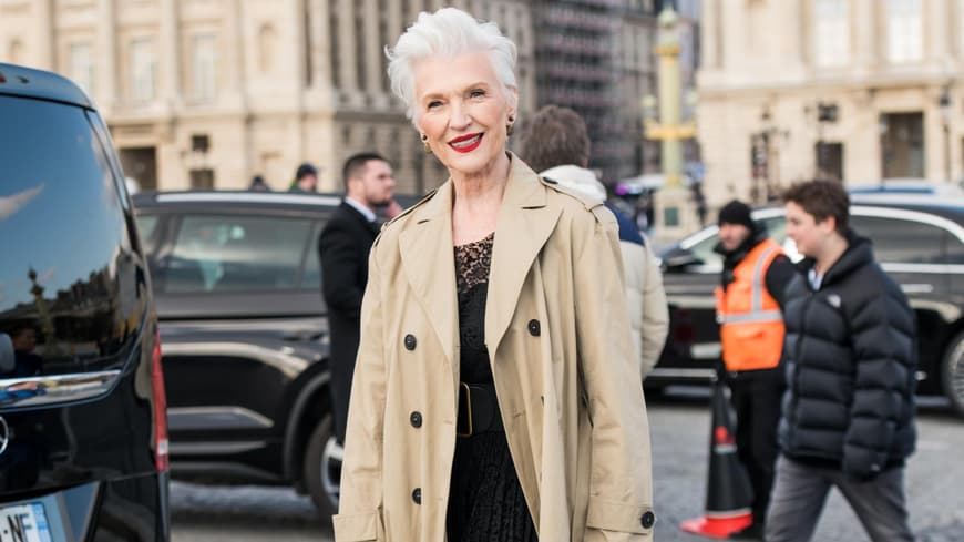 Maye Musk auf Dior Show 2023 mit beigem Trenchcoat und schwarzem Kleid Streetstyle lässige Kleidung für Frauen ab 60