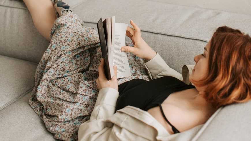 Frau liest ein Buch auf der Couch