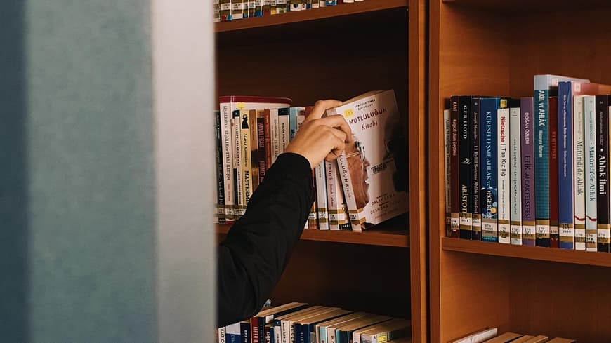 Frau greift in ein Bücherregal