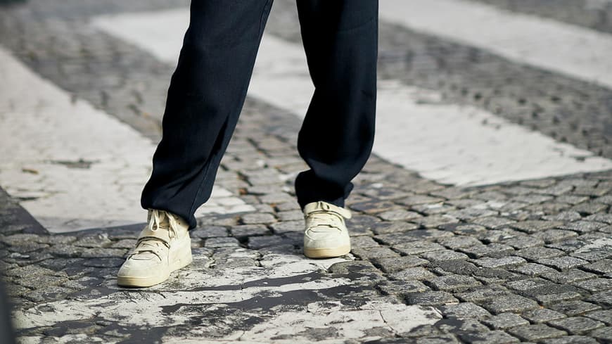 Frau mit schwarzem Outfit und Sneakern