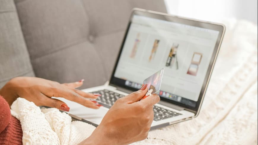 Frau vor dem Laptop mit einer Kreditkarte in der Hand