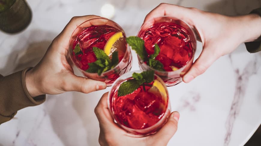 Freundesgruppe stößt mit roten Cocktails an