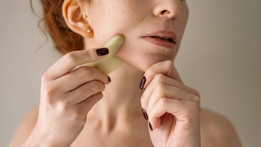 Frau benutzt Beauty Tool Gua Sha Stein