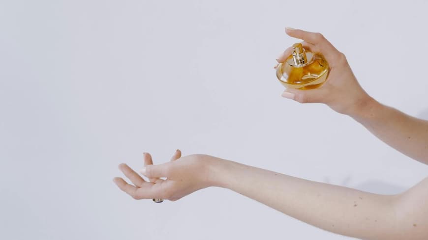 Frau sprüht Parfum auf ihren Unterarm
