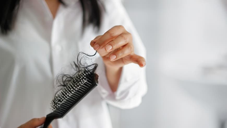 Eine Frau hält eine Bürste mit Haaren in der Hand