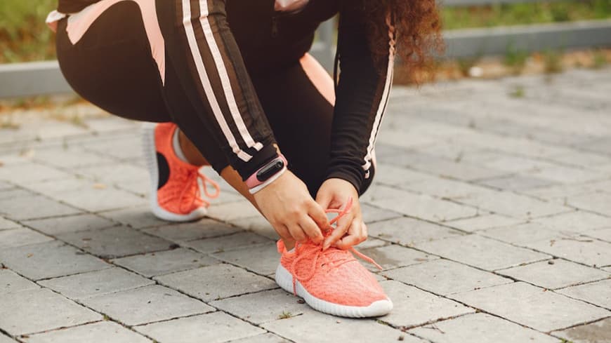 Eine Frau bindet sich ihren Sportschuh fest