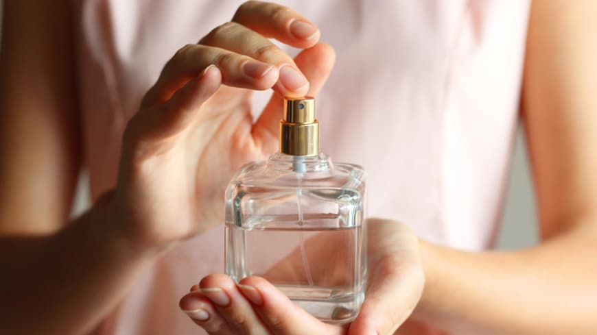 Eine Frau hält ein Parfüm in der Hand