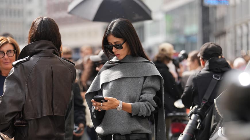 Frau mit grauem Outfit schaut auf ihr Handy