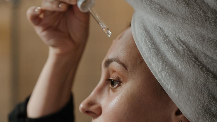 Eine Frau trägt ein Serum auf ihr Gesicht auf