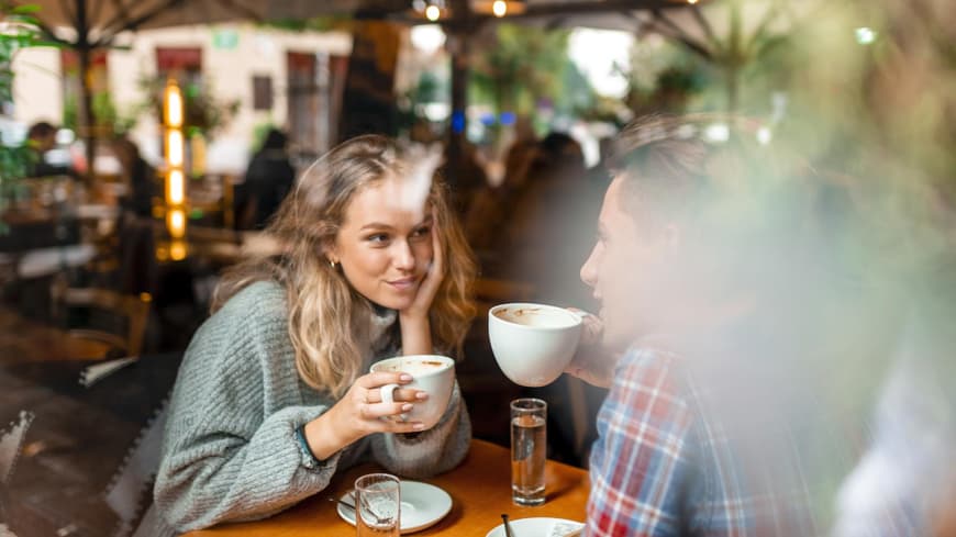 Mann und Frau sitzen sich gegenüber und trinken Kaffee