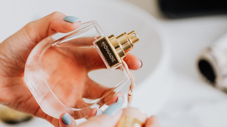 Frau hält ein Parfum in der Hand