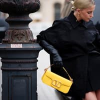 Caro Daur mit einer gelben Designer-Handtasche