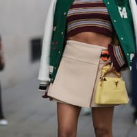 Frau trägt einen kurzen Minirock und eine Designer-Handtasche von Louis Vuitton