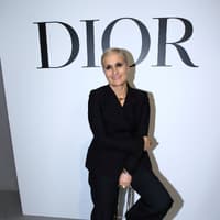 Maria Grazia Chiuri: Alles über die erste weibliche Kreativdirektorin an der Spitze von Dior Maria Grazia Chiuri sitzt vor Dior Schild