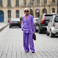 Frau mit violettem Hosenanzug und grauen Haaren