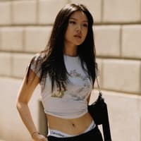 Streetstyle Mailand Fashion Week Frau trägt Rock und Shirt und Boots