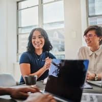 Vier Kollegen sitzen an einem Tisch und lachen