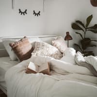 Bett mit weißer Bettwäsche im Schlafzimmer