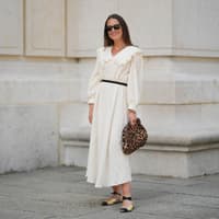 Frau in weißem Kleid und Leo-Tasche