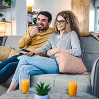 Paar sitzt auf der Couch und guckt Fernsehen