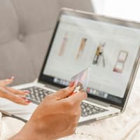 Frau vor dem Laptop mit einer Kreditkarte in der Hand