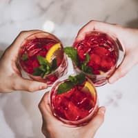 Freundesgruppe stößt mit roten Cocktails an