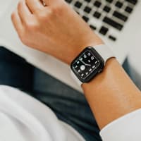 Frau am Laptop schaut auf Uhr