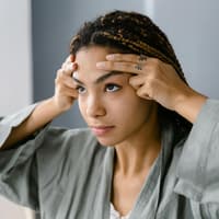 Frau legt ihre Finger auf die Stirn