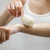 Frau seift sich mit Duschgel ein