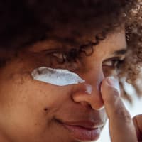 Pickel von Sonnencreme: So wirst du sie wieder los Pickel von Sonnencreme: Frau trägt sich Sonnenschutz auf das Gesicht auf