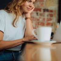 Junge Frau sitzt mit ihrem Laptop in einem Café