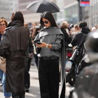 Influencer Herbst-Trends 2025 Frau mit grauem Outfit schaut auf ihr Handy