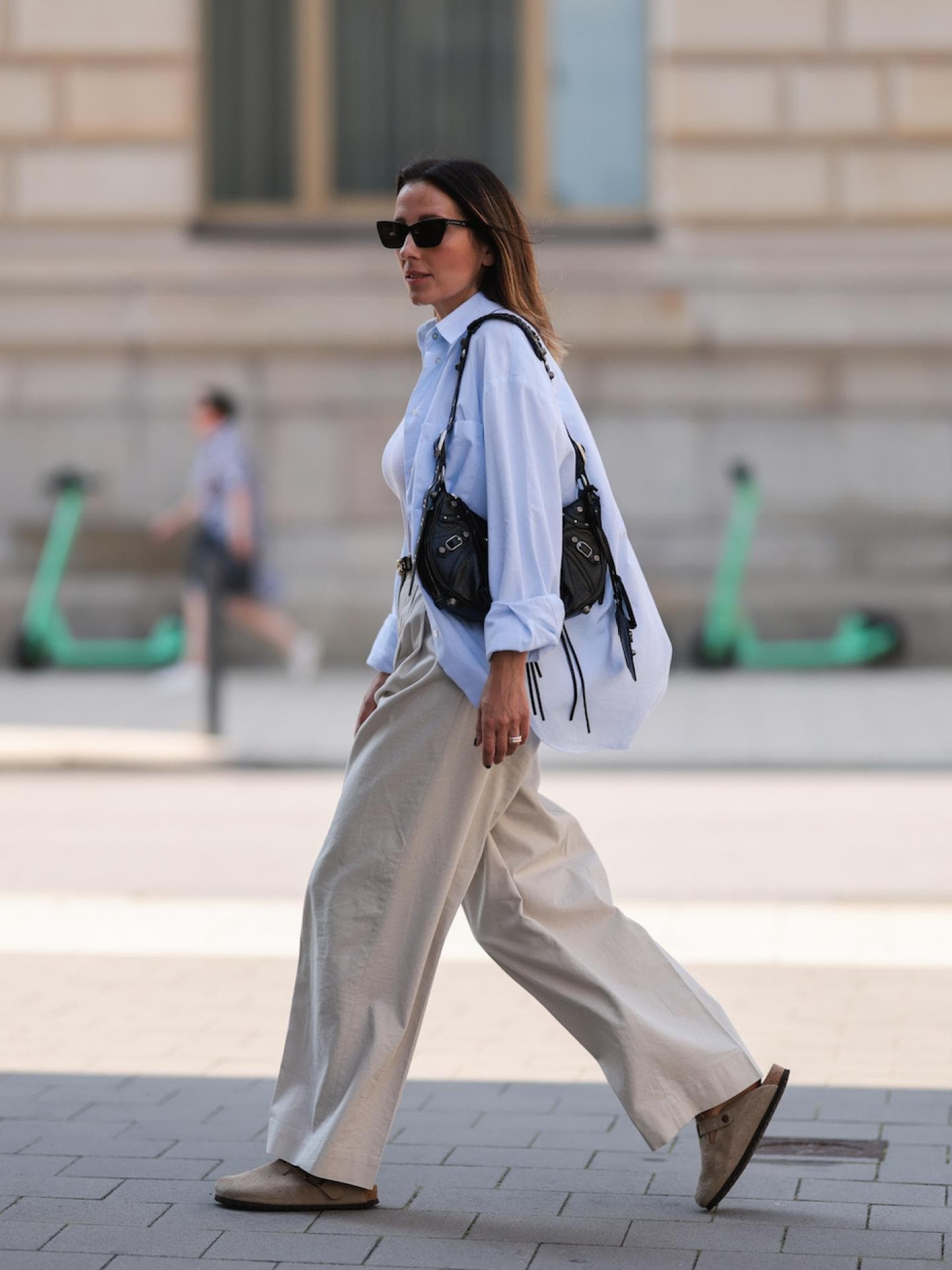 Frau trägt Birkenstocks, eine weiße Bluse und eine Leinenhose