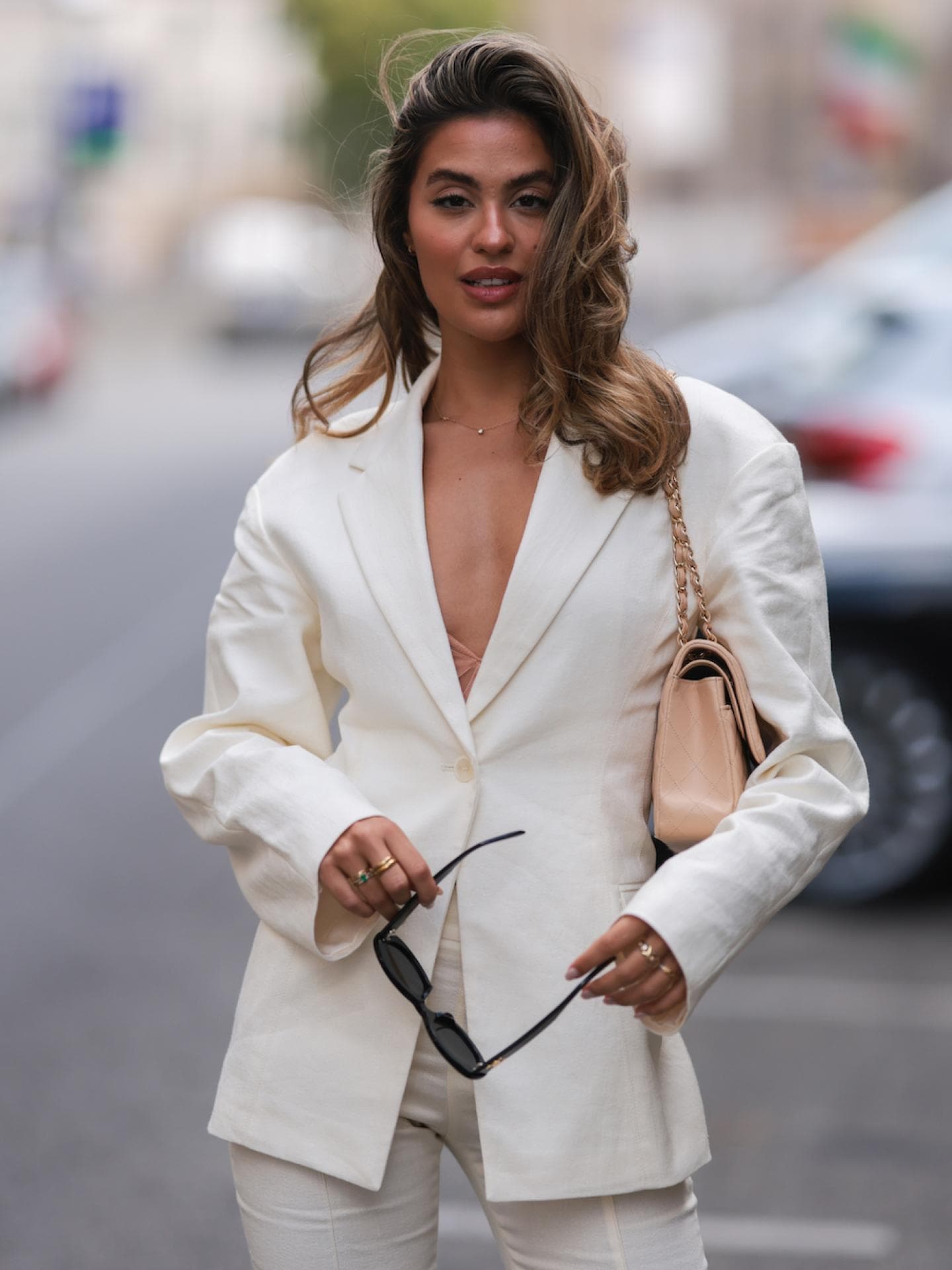 Frau trägt einen hellen Leinen-Blazer mit beiger Chanel-Tasche
