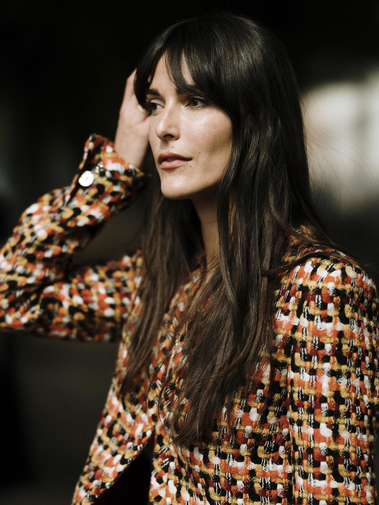 Paris Fashion Week Streetstyle Frau trägt Jacke mit Karomuster lange braune Haare und Pony