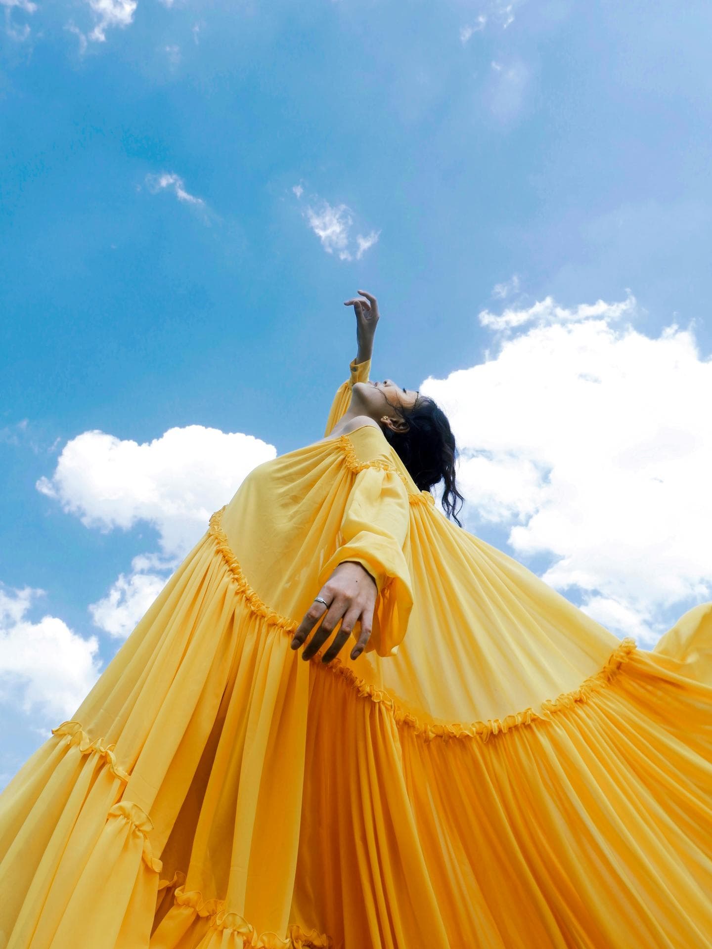 FRAU MIT Gelbem Kleid vor blauem Himmel