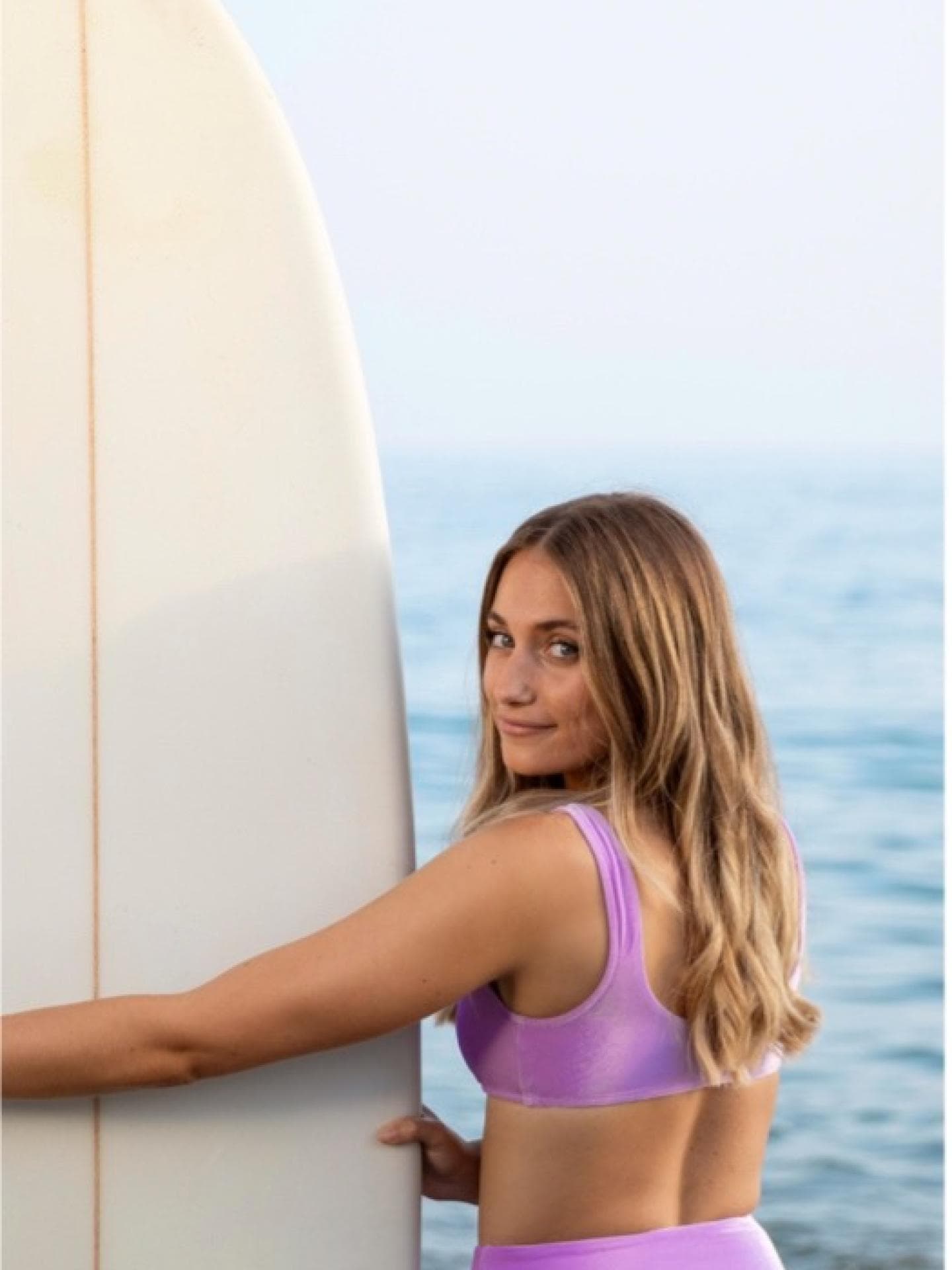 Eine Frau hält ein Surfbrett in de Hand