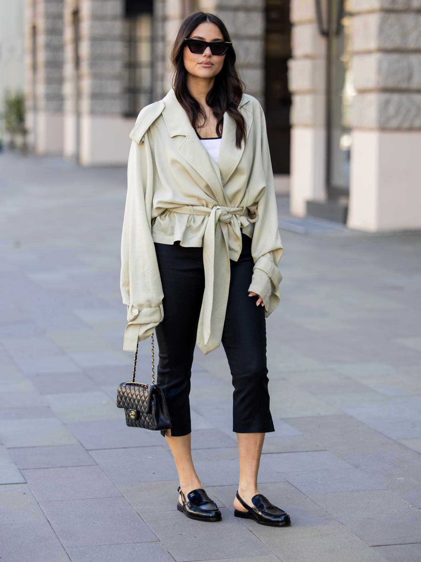 Caprihose kombinieren Frau in beiger Trench-Jacke kombiniert mit einer schwarzen Caprihose
