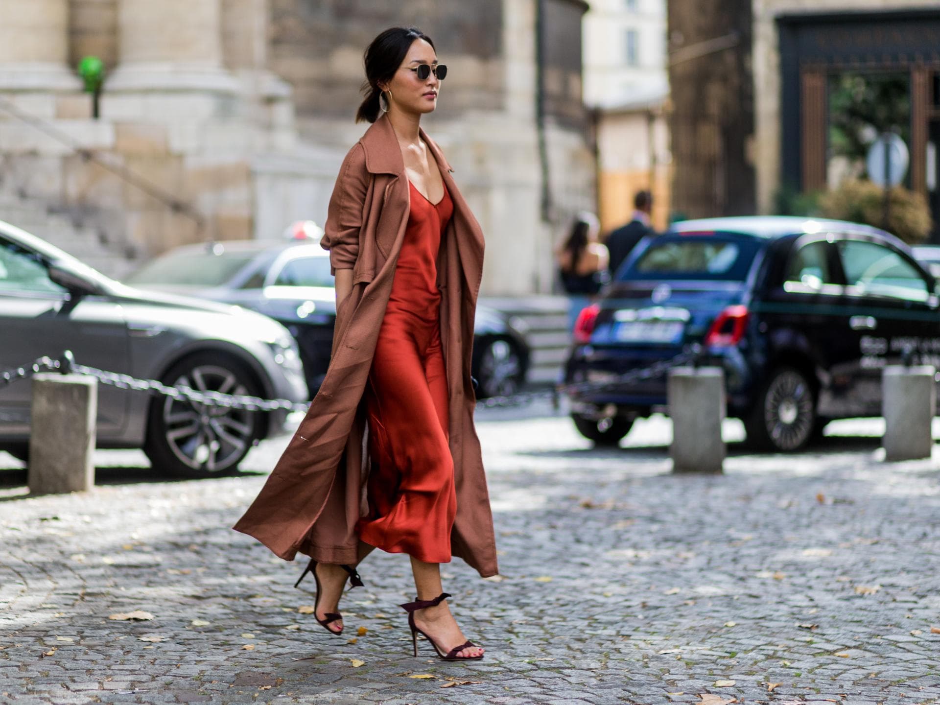 Frau in einem rostroten Slip Dress mit einem Trenchcoat