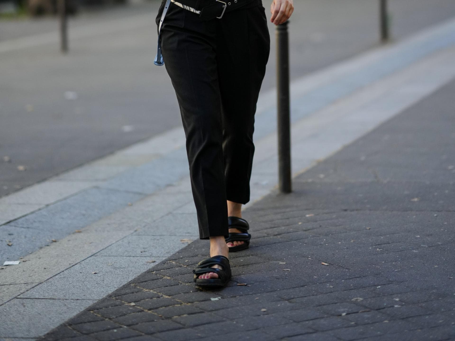 Frau trägt Sandalen schwarze Hose und schwarz-weißes Oberteil